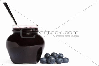 jam jar with blueberry jam a spoon and blueberries aside