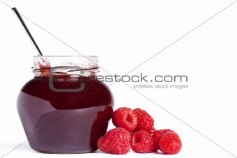 jam jar with a spoon and raspberries aside 