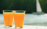 two glasses of orange juice against sea