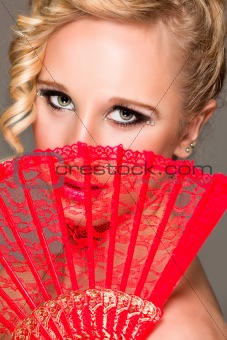Portrait of girl closing face with textile fan. Retouched
