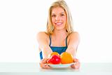 Cheerful lovely girl sitting at table with plate of fruits
