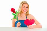 Lovely girl sitting at table with rose and Valentine heart
