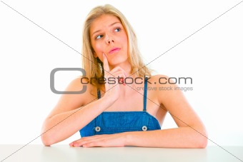 Thoughtful beautiful girl sitting at table 
