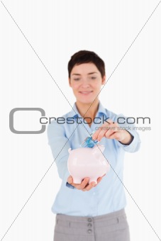 Bank worker putting a bank note in a piggy bank