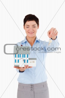 Real estate agent showing keys and a miniature house