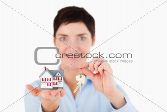 Close up of a woman showing keys and a miniature house