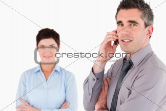 Businessman making a phone call while his colleague is posing
