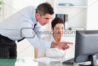 Businessman pointing at something on a screen to his secretary
