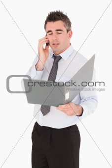 Portrait of a businessman making a phone call while holding a binder
