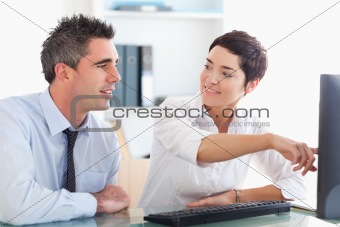 Office worker pointing a something on a screen to her colleague