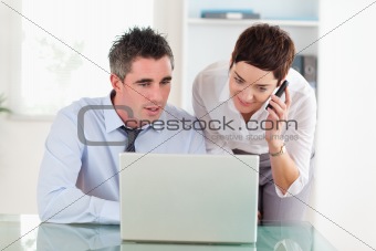 Coworkers working with a laptop and a cellphone