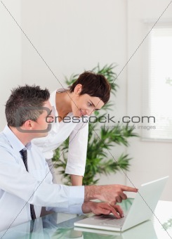 Portrait of a man pointing at something to his colleague on a laptop