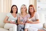 Charming women sitting on a sofa with cups