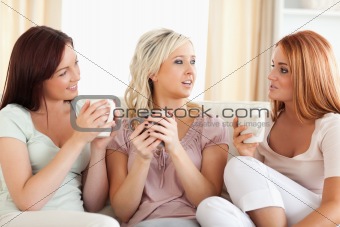 Women sitting on a sofa with cups