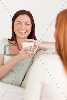 Happy young Women sitting on a sofa with cups