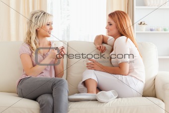 Charming young Women sitting on a sofa with cups
