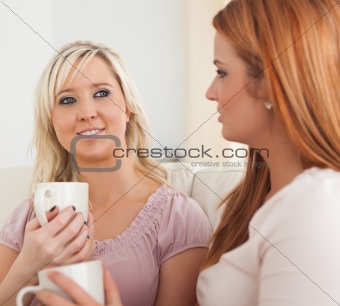 Cute Young Women sitting on a sofa with cups