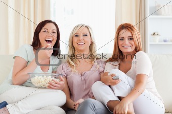Cheerful Friends lounging on a sofa watching a movie