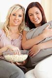 Smiling women lounging on a sofa watching a movie