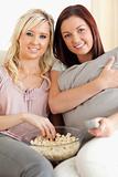 Cheerful women lounging on a sofa watching a movie
