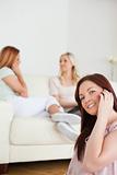 Smiling young Women chatting on a sofa one has a phone
