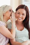 Smiling young woman telling her friend a secret