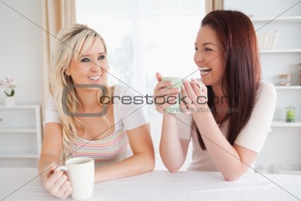 Cheerful Women sitting at a table with cups
