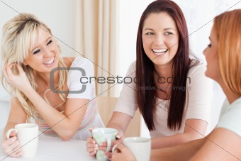 Joyful young Women sitting at a table with cups