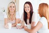 Charming young Women sitting at a table with cups