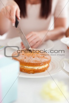 Charming Woman sitting at a table cutting a cake