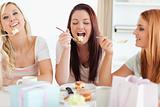 Cute Women sitting at a table eating a cake