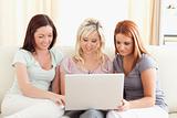 Cute women sitting on a sofa with a laptop