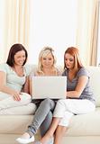 Laughing young women sitting on a sofa with a laptop