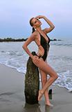 Pretty woman in swimsuit bikini arching her back on a beach