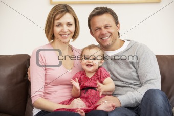 Parents And Baby Daughter On Sofa