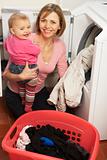 Woman Doing Laundry And Holding Baby Daughter