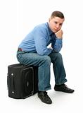 pensive young man sitting on a hand bag