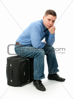pensive young man sitting on a hand bag