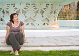 young beautiful woman relaxes in front of fountain at sunset