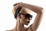 fashion shot of blond girl with sunglasses posing against white 