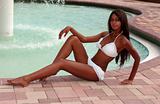 Portrait of beautiful African American woman in pink bikini sitting time on a side of swimming pool