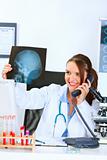 Smiling doctor woman talking on phone and holding patients roentgen
