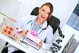 Surprised doctor woman sitting at office table and holding gift in hands
