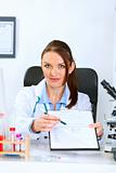 Doctor woman sitting at office table with document and pen for signing   

