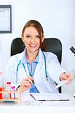 Smiling doctor woman sitting at table and giving medical prescription
