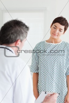 Woman in hospital gown talking to her doctor