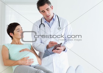 Pregnant woman lying down talking to her doctor
