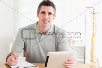 Male Doctor sitting working with a tablet and a chart