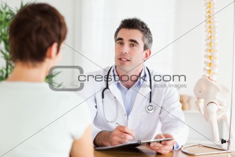 Male Doctor writing something down while patient is talking