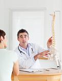 Male Doctor showing a female patient a part of a spine